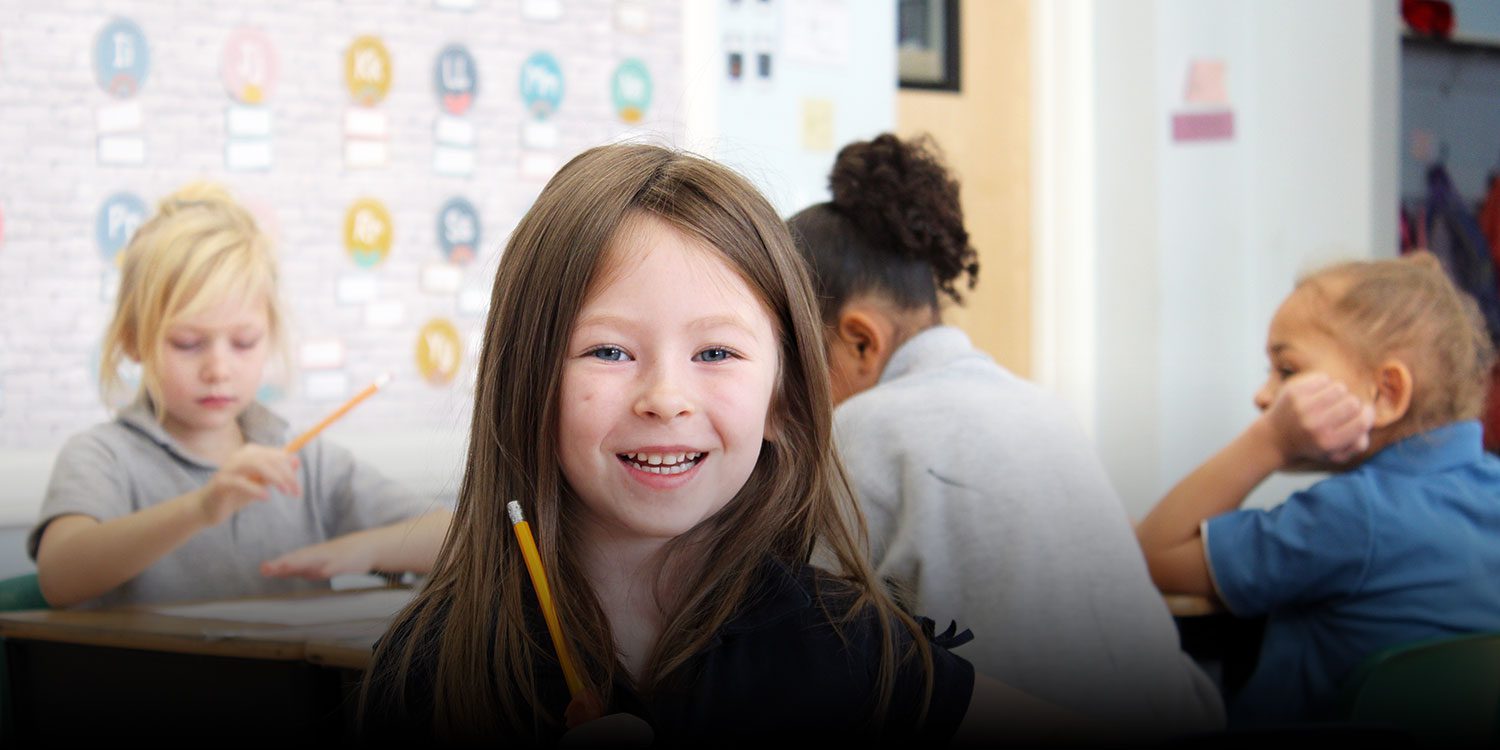 Smiling student in a classroom sitting at a desk