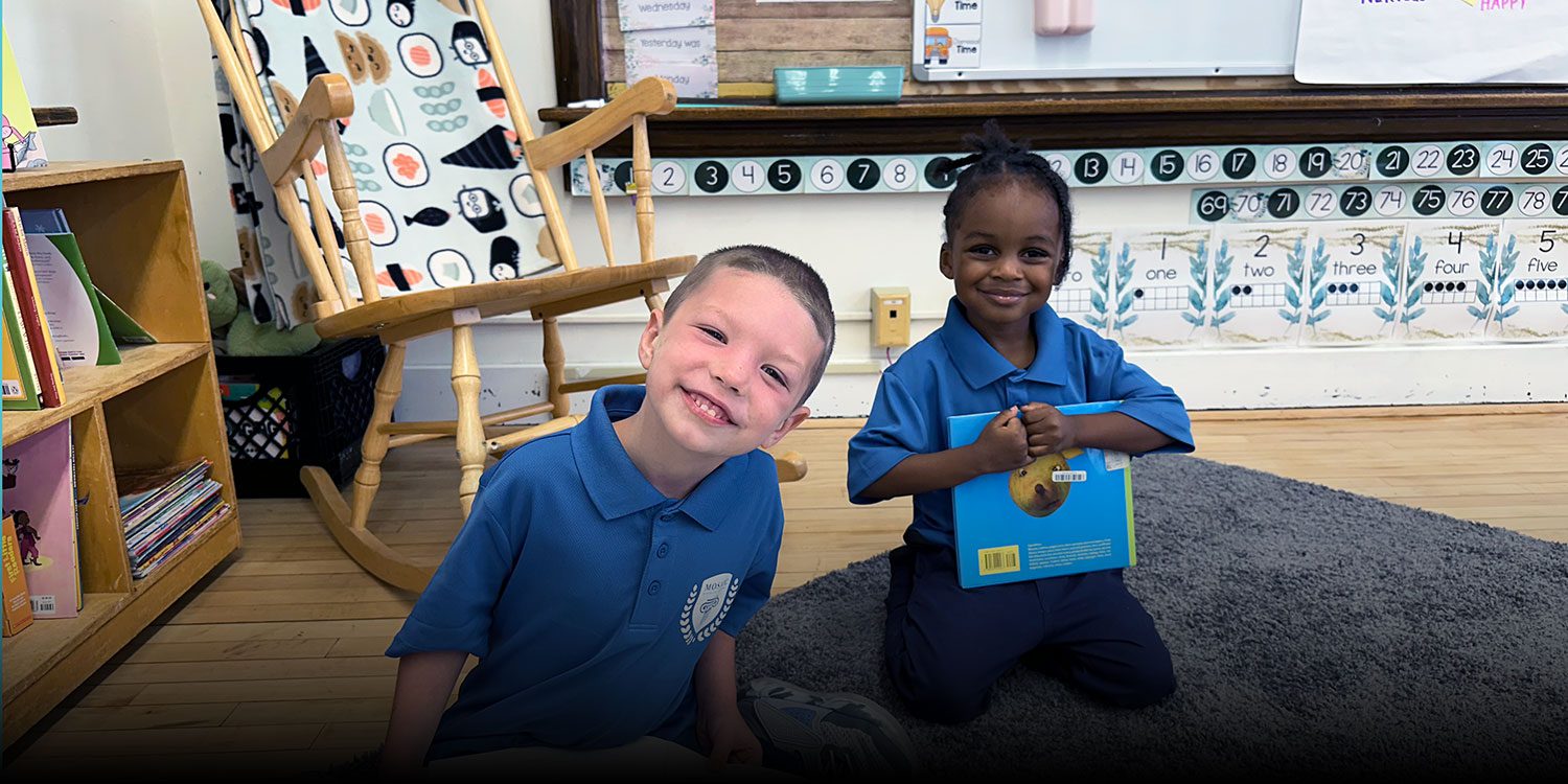 Smiling elementary students sitting with books in a classroom library